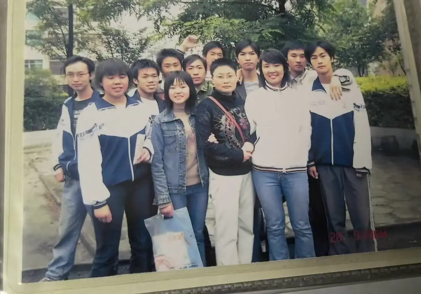 2006年语文课堂外的温馨瞬间，212班同学们围绕在语文老师身旁的合影。老师手中还拿着刚讲解完的《滕王阁序》课本，而我们青涩的笑容里满是对未来的憧憬，文学滋养的青春在快门声中永恒定格。